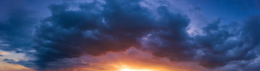 Naklejka na ściany i meble Dawn with storm clouds, crimson sky and sunshine.