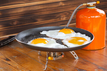 fried eggs in a skillet on a portable camping stove.