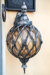 Wall-mounted round forged street lamp in an elegant metal braid.