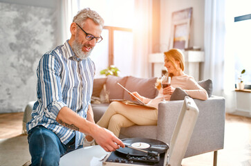 Mature couple are sitting at home on the couch, relaxing, enjoying life, drinking wine and...
