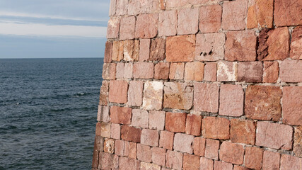 Muro de piedra rojiza junto al mar