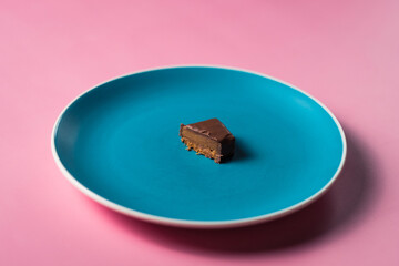 Uneaten slice sweet dessert chocolate bar on colored plate on pink background. 