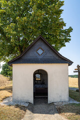 Fototapeta na wymiar Small chapel in landscape with huge tree in the background