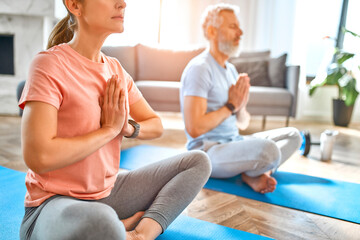 Obraz premium Sport, fitness and healthy lifestyle concept. Mature couple doing exercise or yoga at home. How to stay healthy in quarantine.