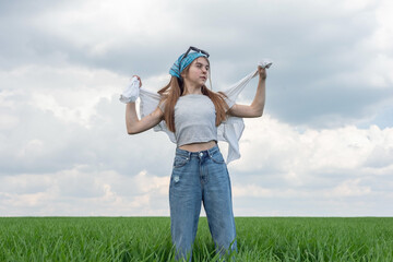 fashionable little teenager girl, in a field of green grass, against a background of cloudy sky