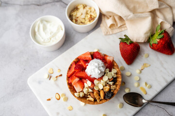 Yogurt parfait in waffle bowl. Greek yogurt in ice cream waffle bowl with fruit and nuts, healthy diet friendly dessert. Fruity waffle bowl