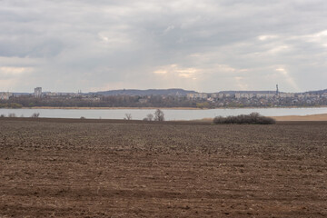 plowed field against the background of clouds and sunbeams. Spring cleaning of the land, preparation for planting crops