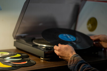 hands put a vinyl record on a turntable