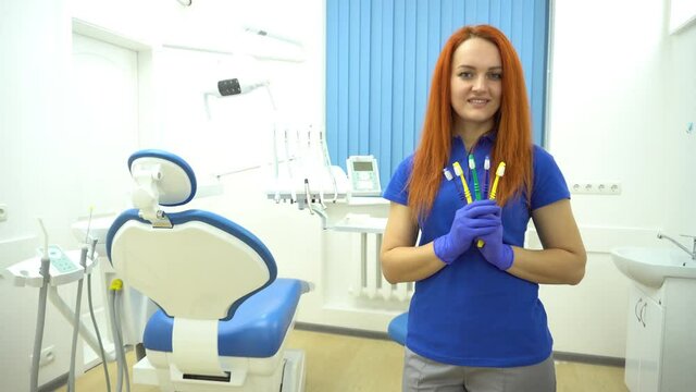 4K Woman dentist holding professional toothbrushes in hands and looking at camer