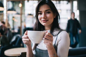 Satisfied woman enjoying coffee in cafeteria