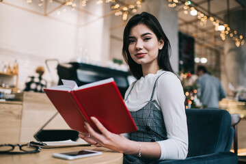 Positive female student with notebook in cafe