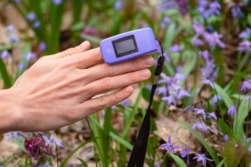 Pulse oximeter on a finger. Violet oxygen saturation meter (SPO2). Device outdoors close-up with...