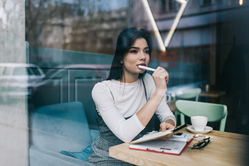 Thoughtful woman working with notes in cafe