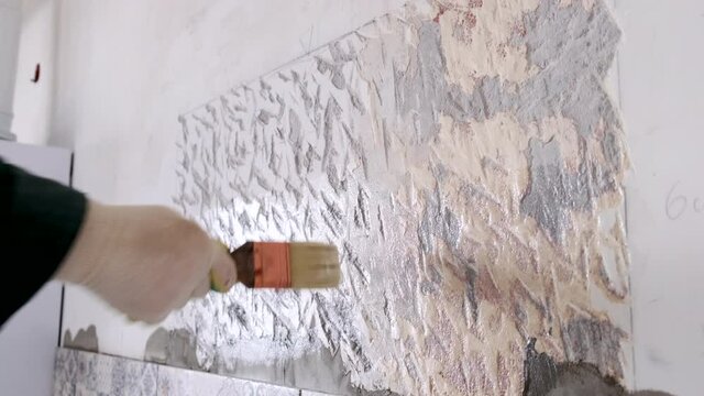 Men's hand with a brush puts on the wall primer