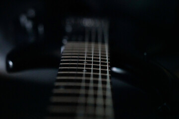 Closeup shot of a black electric guitar fragment with strings