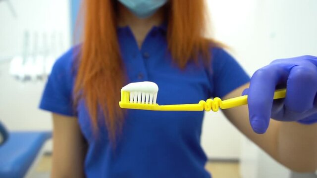 Slow Motion Young dentist holding a yellow toothbrush in hand. Focus on the toot