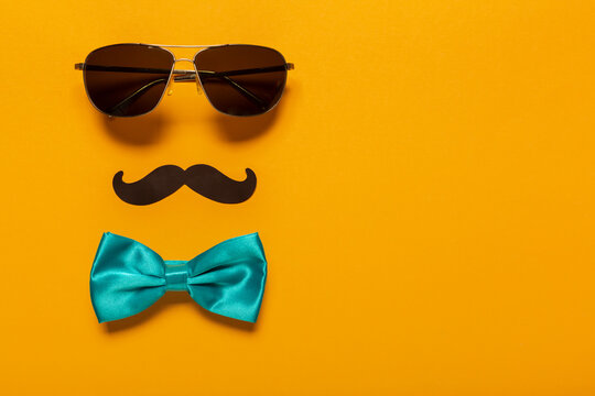 Glasses, mustache, and blue bow as a symbol of father's day with free space for text, greeting card for holiday. Celebration of a family holiday.
