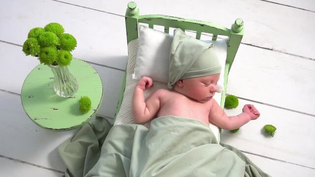 Beautiful newborn baby girl lying on stylized green bed. Cute portrait of infant