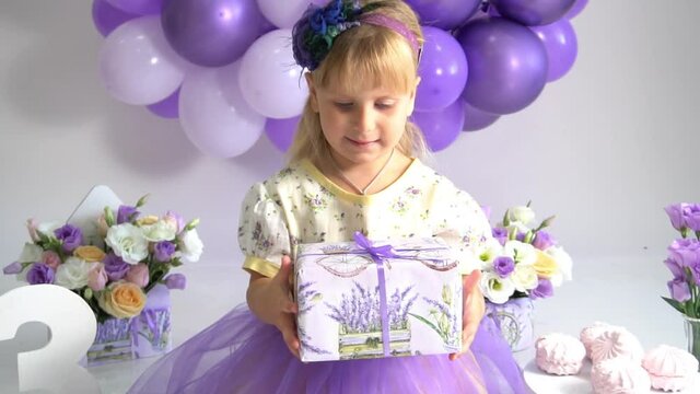 Slow Motion Cute funny baby girl year play with gift box. Birthday party