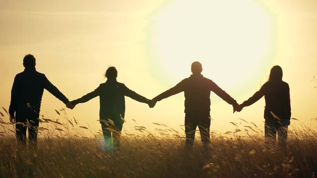 Silhouette Family Teamwork Team People Holding Hands Sunset business team joins hands for business success. Family silhouette together hand in hand. Teamwork of four people for a successful work.