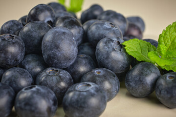 Very close up image of blueberries heaped up with some green leaves