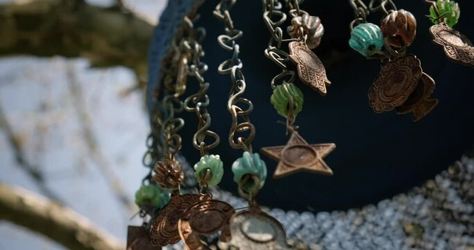 Low angle shot of charms with hamsa hand symbols hanging and moving slightly on the wind.