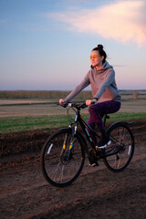 Summer, field, sunset, beautiful sky. The girl rides a bike.