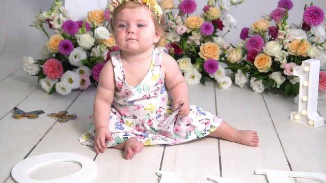 Birthday girl 1 year sitting in the photo zone surrounded by flowers