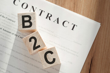 Word B2C - (Business to Consumer) on wooden cubes on contract documents background.