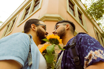 Fototapeta premium Pareja de novios gay mirándose cara a cara de cerca con un ramo de flores amarillas 