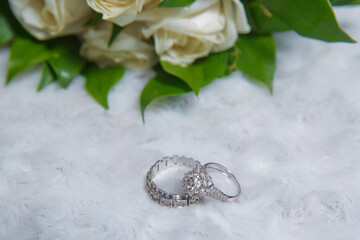 Wedding engagement rings on the background of a beautiful bouquet of roses . Stylish white wedding flower Rings in front of the wedding bouquet .