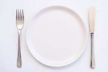 Clean empty white plate with knife and fork