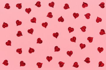 Red heart shaped confetti pattern on pink abstract background.