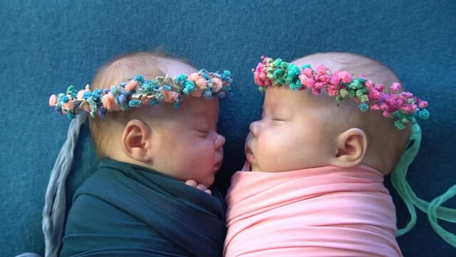 Slow Motion newborn twin kids sleeps together on blue fabric