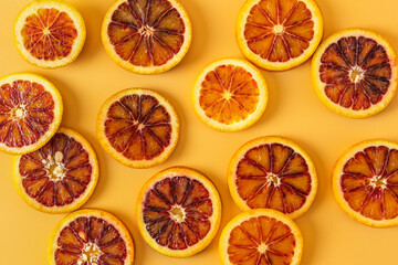 Group of fresh organic Sicilian blood oranges sliced over yellow background. Flat lay.