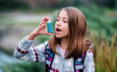 Little girl using asthma inhaler. Health care concept