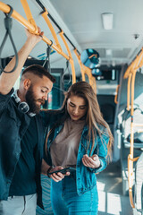 Plakat Young couple in love using smartphone in a bus