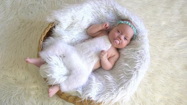 Beautiful newborn baby girl sleeping in basin filled white fur. Cute portrait of