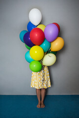 birthday girl with colored balloons on gray background