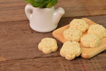 Malaysian traditional cookies called as KUIH BANGKIT CHEESE on wooden plate served during Eid Mubarak.