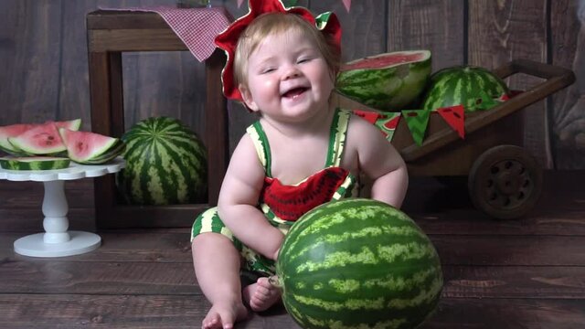 An adorable baby girl happily preparing to dig into a watermelon