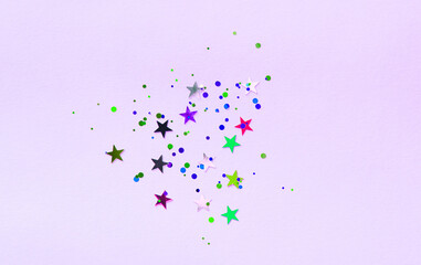 Lilac background with multicolored glitter and stars. Party background with confetti.