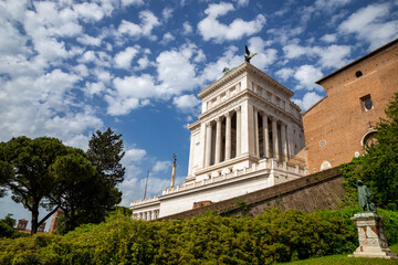 Detail of the altar of the Fatherland with a blue sky full of clouds the statue of Cola di Rienzo, from the steps of the Campidoglio, in the center of Rome.On a day with green vegetation.