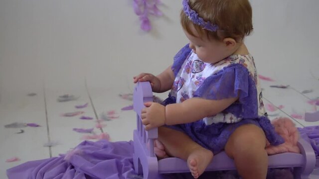 beautiful little girl posing in violet dress. Background with a feathers