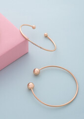Two modern golden bracelets with diamonds on pink and blue