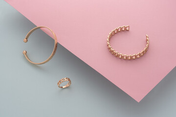 Modern bracelets and chain shape ring on pink and blue paper background