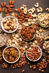 Obraz na płótnie Canvas Selection of assorted raw nuts and various seeds in bowls on brown stone background from above, healthy source of energy, fat and vegetarian protein