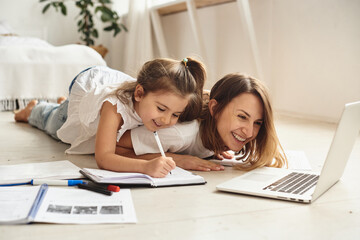 mom works at the computer while playing with her daughter