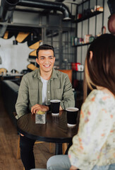 Young couple sitting in coffee shop chatting and drinking coffee