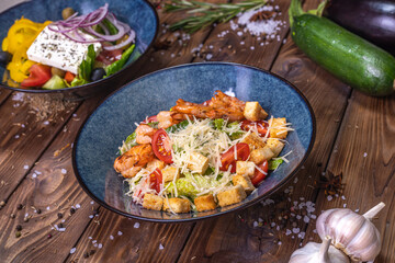 Salad with shrimps, grated cheese, tomatoes, crackers, lettuce leaves on a wooden background.
